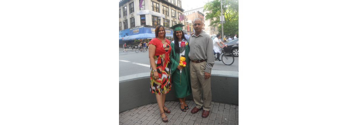 Ashmera standing between her parents after her high school graduation holding a rose and stuffed animal.