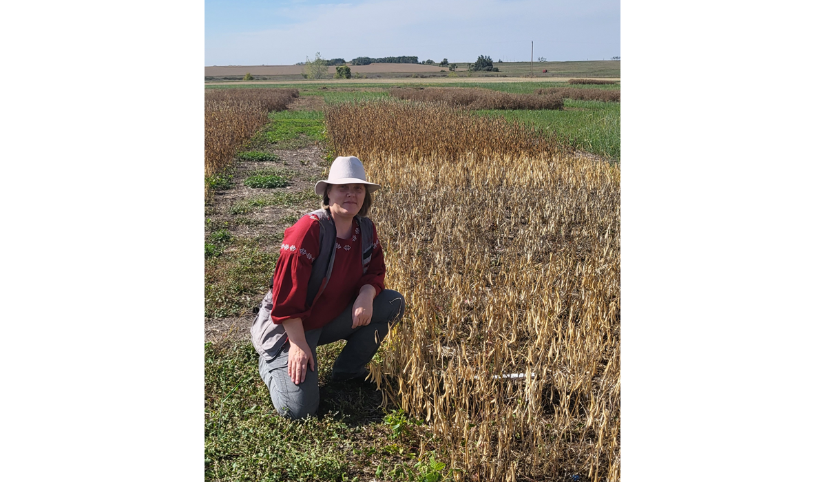 Lana Shaw on one knee in a crop field